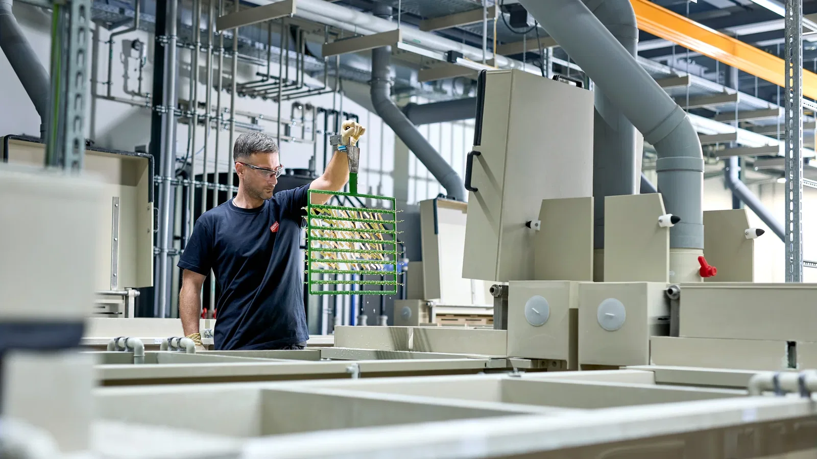 Mitarbeiter der C. Jentner GmbH hebt ein Gestell in der Gestellgalvanik